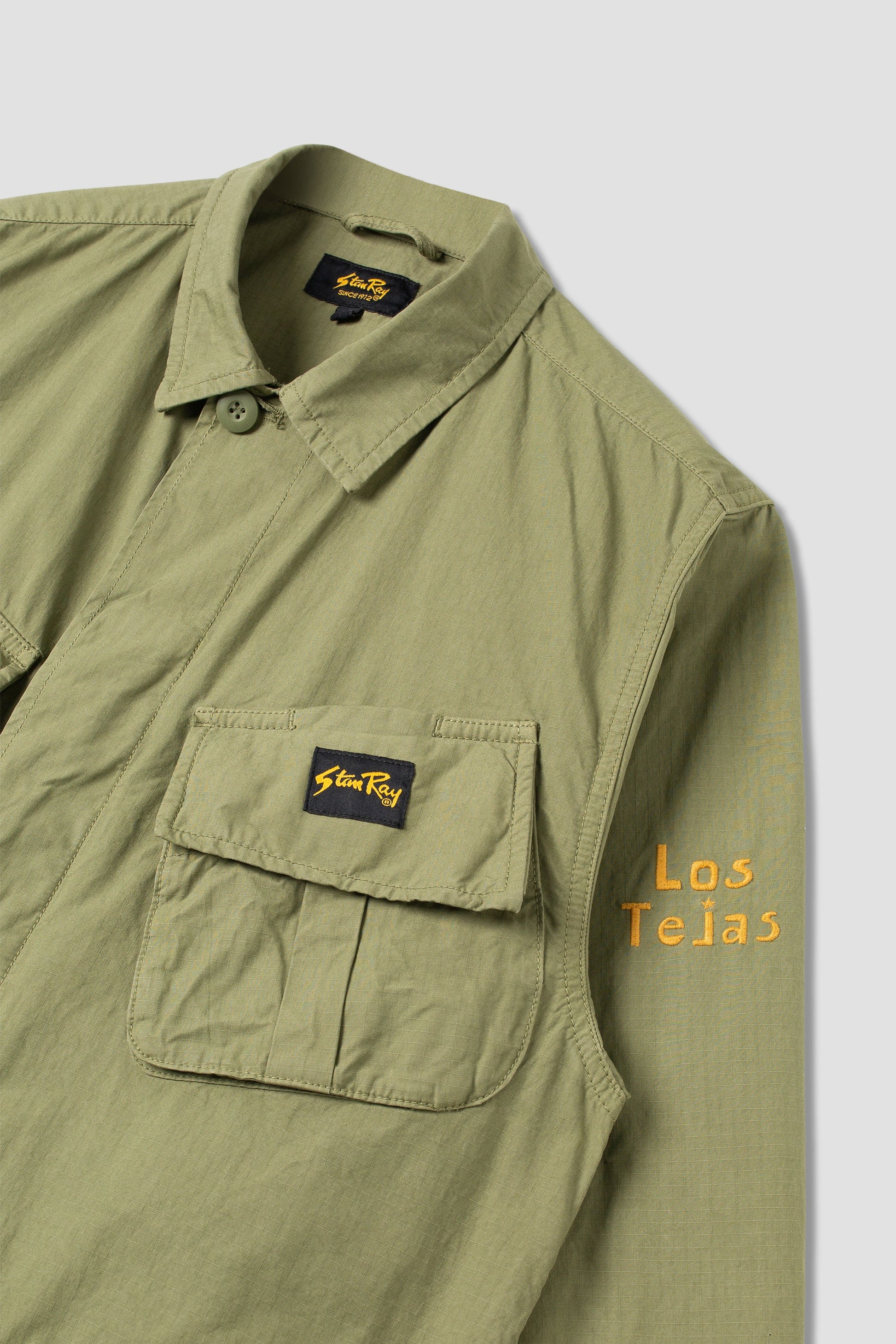 Side view of olive jacket with Los Tejas sleeve print